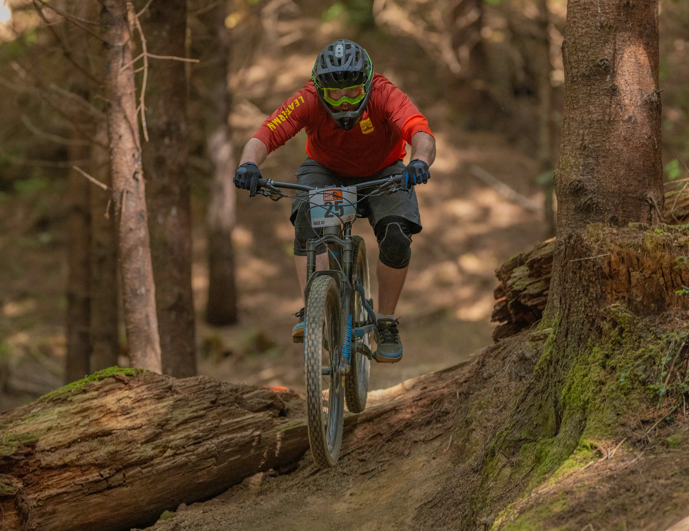 A racer riding over a mossy log at the Whiskey Run Trails during Ride the Dirt Wave